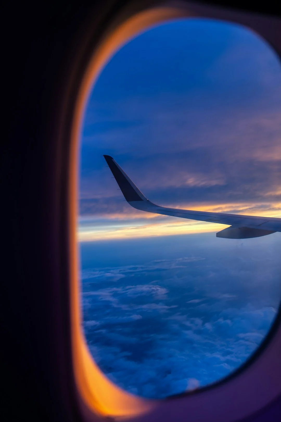 Airplane wing above clouds at sunset